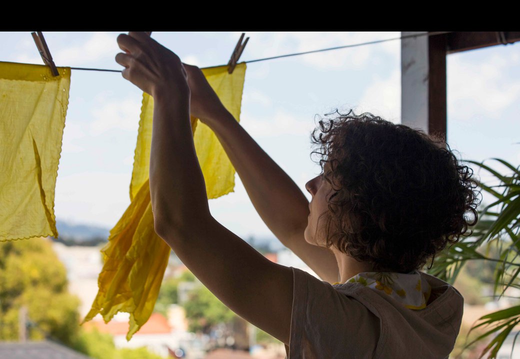Maya Gulassa hanging their dyed fabrics outdoors on a clothesline.