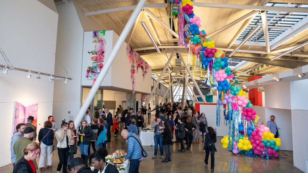 A large hallway full of people and colorful art installations.