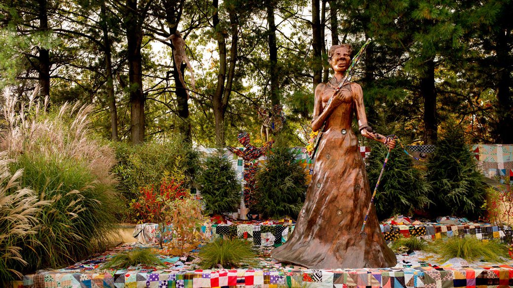 Joyce J. Scott, Araminta with Rifle and Vévé, 2017. Painted milled foam, found objects, milled foam rifle with blown glass and mixed media appliqués, beaded staff Dimensions variable. Figure approx. 132 x 60 x 60 inches. Vévé approx. 60.