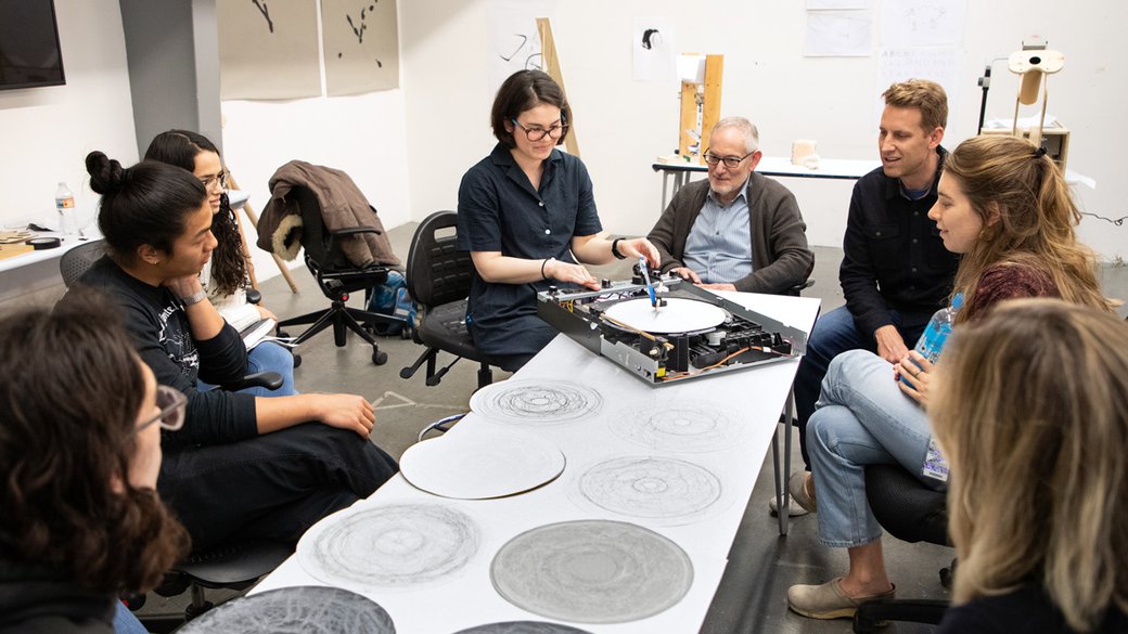 Photograph of MFA Design student Sarah Bonnickson demonstrating her drawing machine for her classmates and professors.