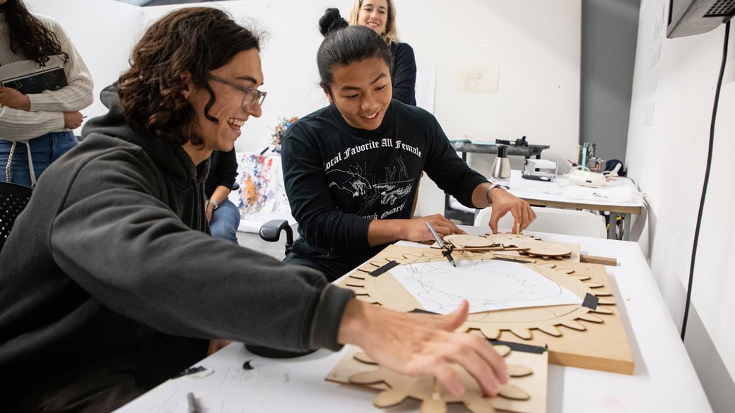 Photograph of MFA Design students Jason Malik and Tin Dinh as they draw in collaboration with Dinh’s machine.