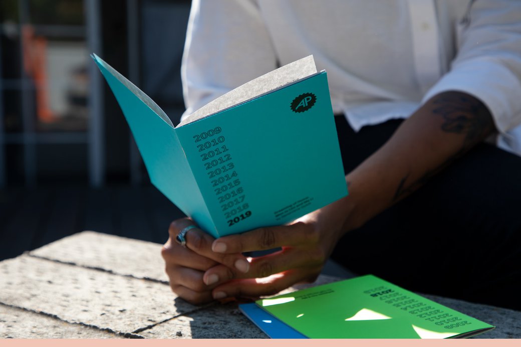 Person holding publication titled There’s No Place Like Home: A Decade of Art Practical zine set.