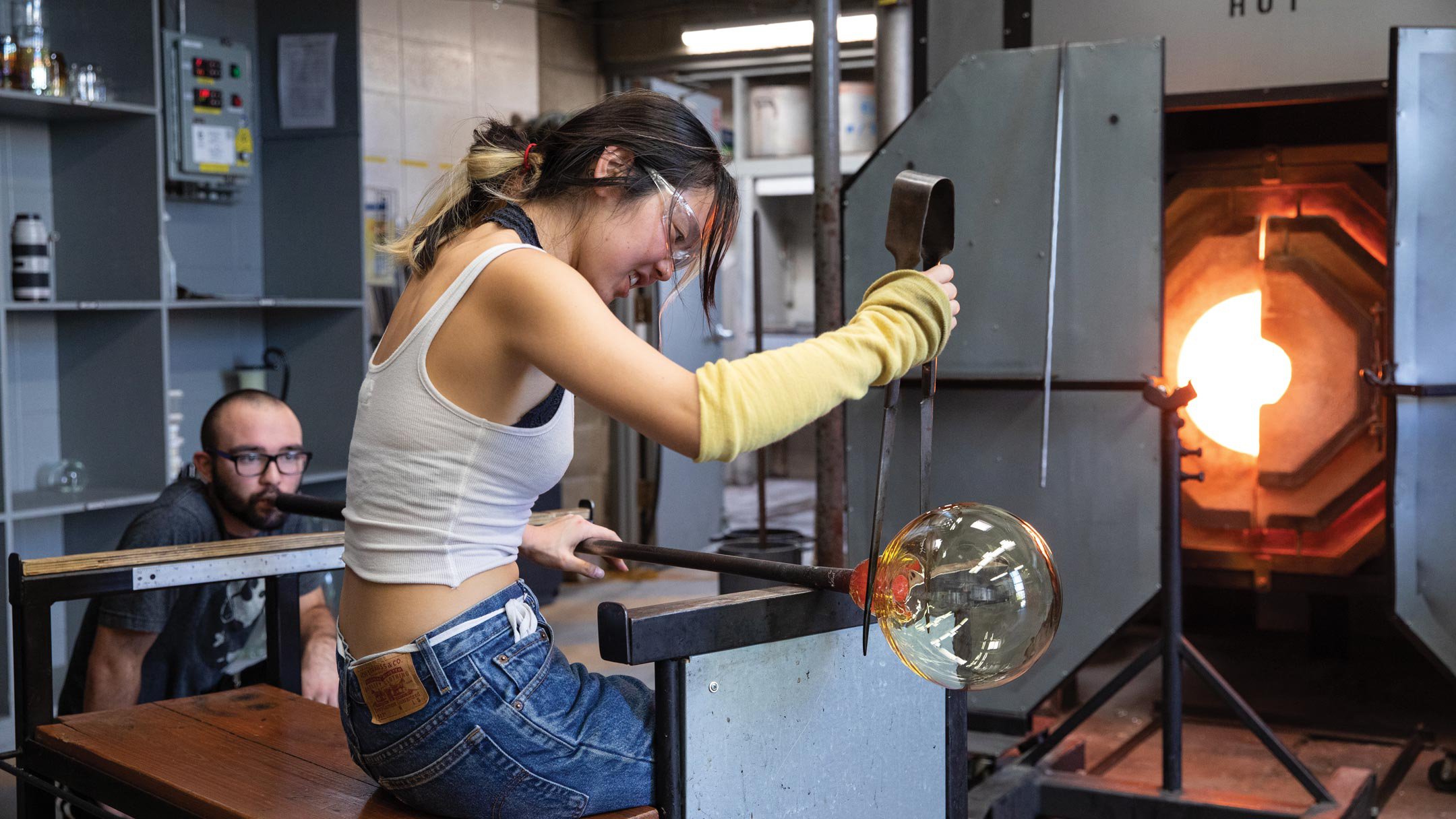 Two students work together on a glassblowing project in the hot shop.