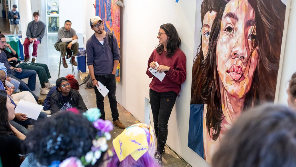 Claire Nichols next to a self-portrait during a senior critique.