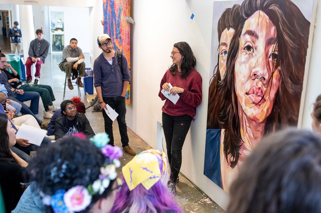 Claire Nichols next to a self-portrait during a senior critique.