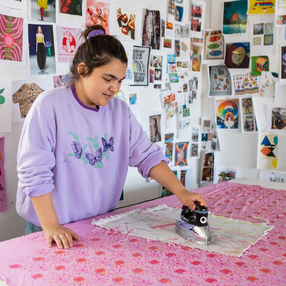 A student irons her newly printed textiles in the studio.