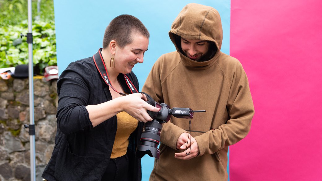 A studio manager smiles as she shows a student his portrait on the camera's LCD screen.