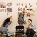 Fashion design students pace their final work on a wall for critiquing.