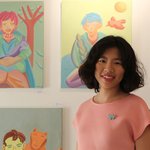 Lihui Liang standing in front of her paintings in a gallery.