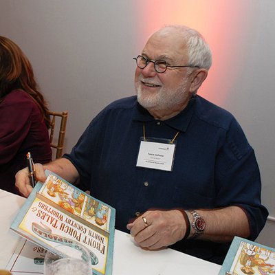 Image of Tomie dePaola holding.a book at a book signing