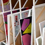 Various paintings dry on a white rack in the Painting and Drawing studios