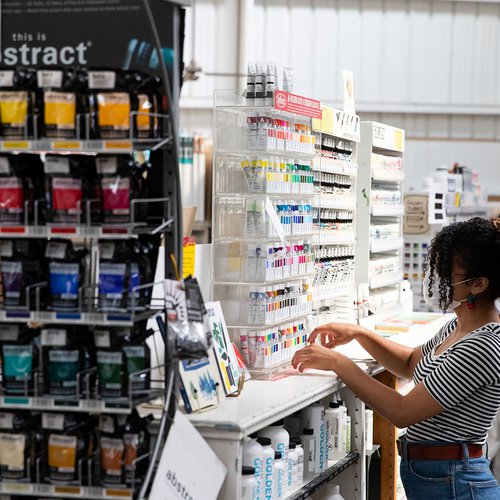 A staff member organizes paints in ARCH Art Supplies.