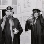 Two students in tams and gowns blow bubbles at the camera.
