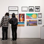 Visitors take in illustrations and graphics arranged neatly on a gallery wall.