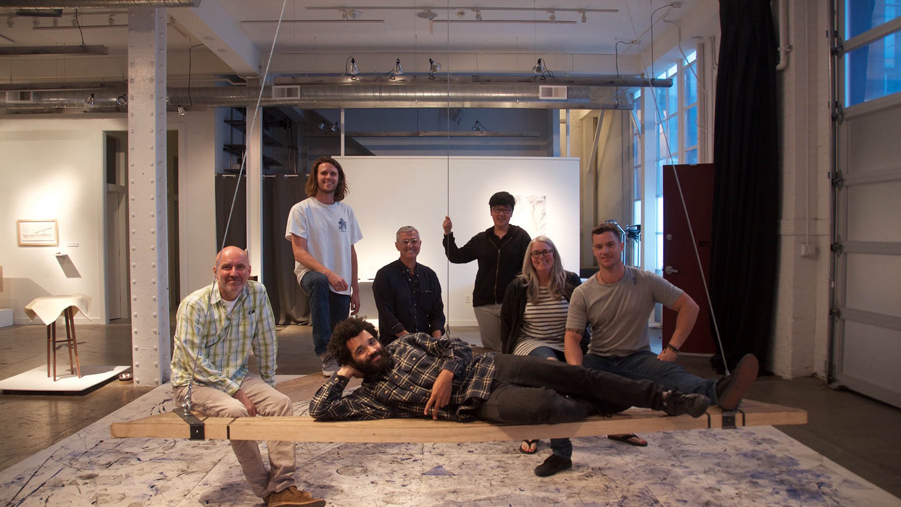 CCA students and faculty sitting on a piece of furniture made for a collaborative thesis exhibition.