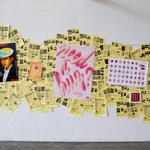 A selection of posters aligned at various angles sits atop a backdrop of yellow pamphlets.