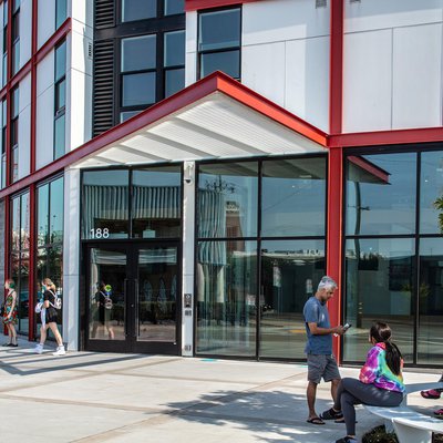 Students mingle outside in the courtyard of Founders Hall, a white building with red gridwork.
