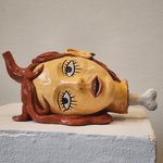 A photo of a sculpture of the bust of a woman with her head down sideways and a bone protruding from the neck