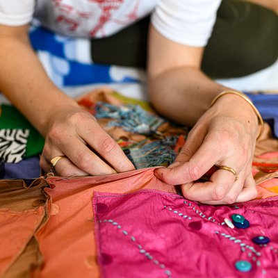 A close-up photo of a pair of hands pinching together shiny pink and orange fabrics.