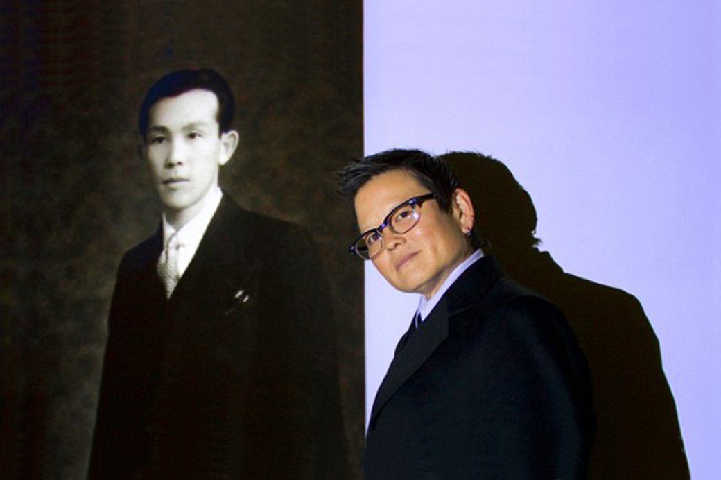 Portrait of Tina Takemoto standing in front of a black and white photo.
