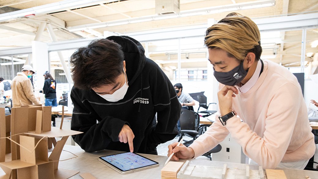 Two students look at a digital tablet in an architecture class.