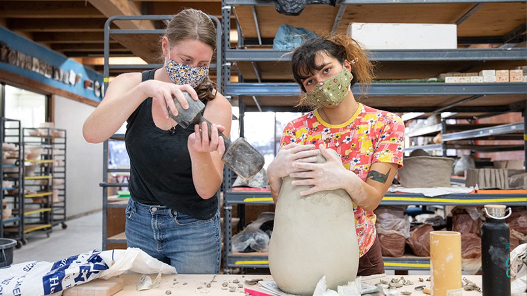 Two students pose behind an oblong-shaped sculpture.