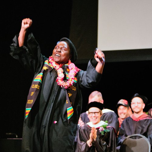 A graduating student celebrates on stage.