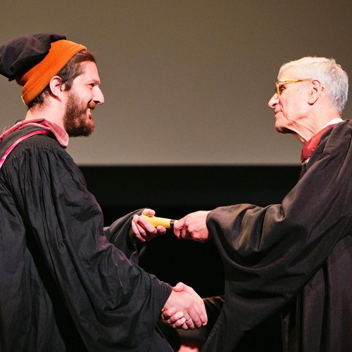 President Stephen Beal shaking a graduating student's hand.