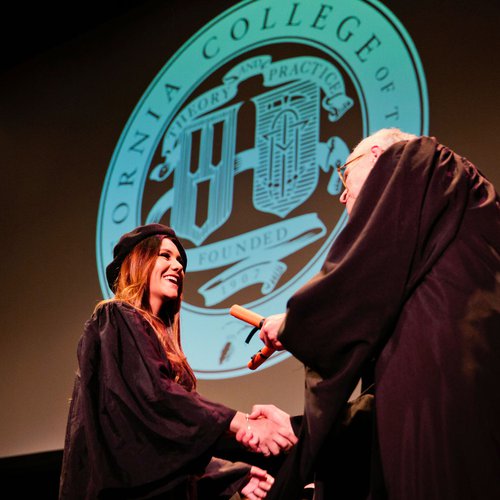 Stephen Beal handing a college degree to a graduating student.