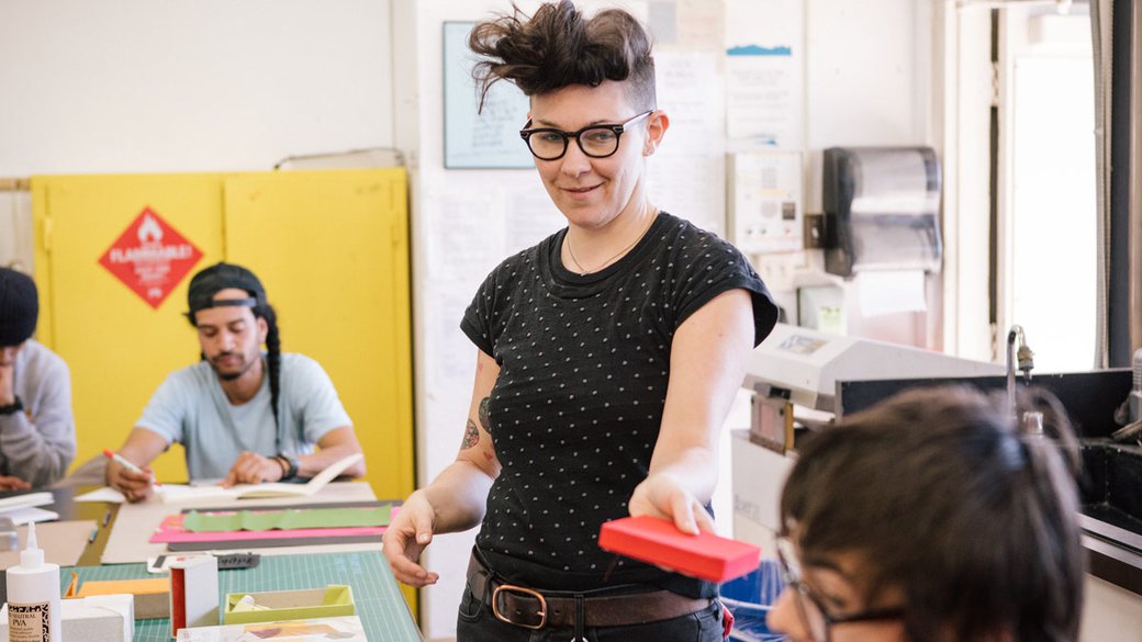 Book Arts Teacher handing something to student