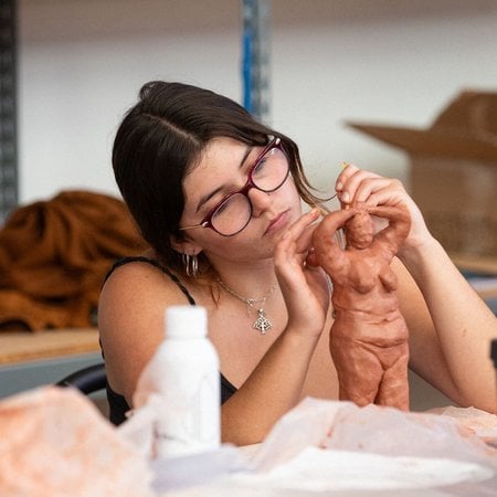 Female artist creating a clay sculpture in CCA's Yoput Programs.