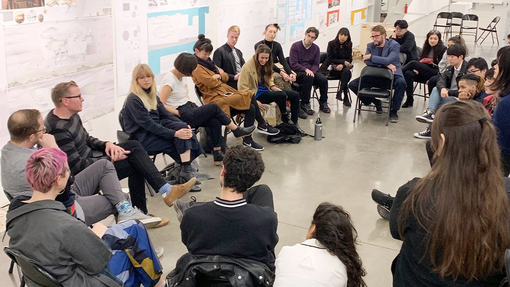 A groups sits in a circle listening to a lecture.