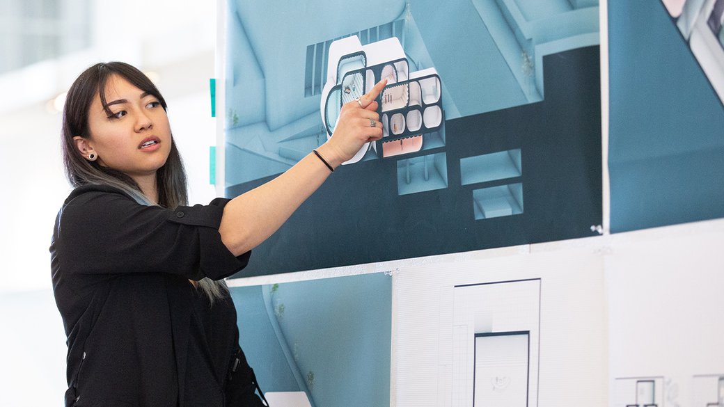 A student points to an architectural rendering.