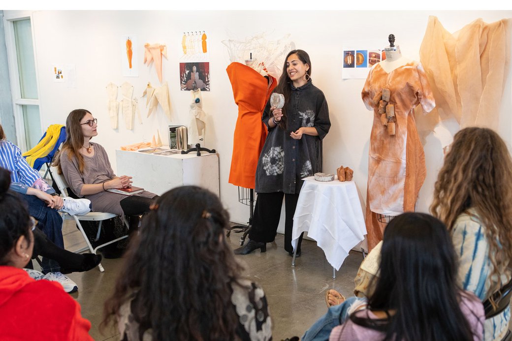 A student presents her conceptual fashion work for a group to critique.