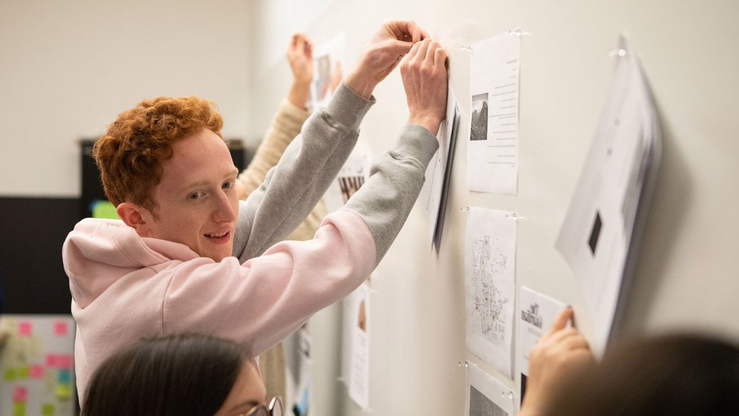 student pinning up their work in the "border phenomena" class