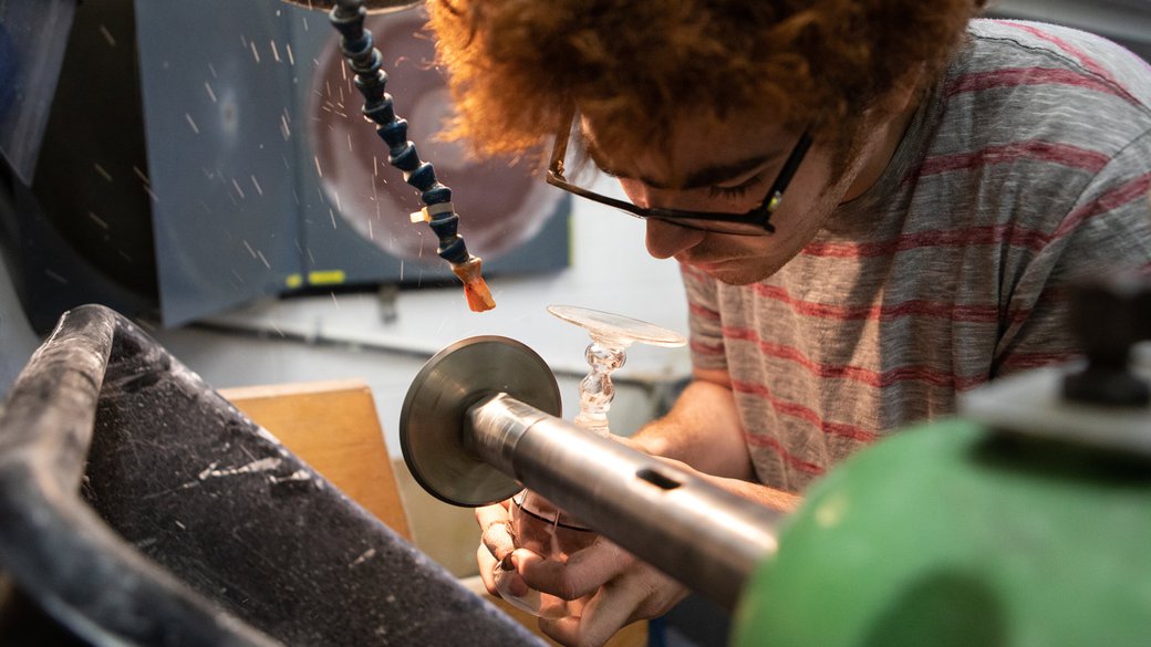 A young man grinds a glass chalice in the Cold Shop.
