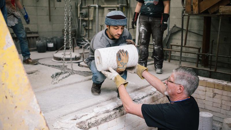 Faculty helps student lift their bronze cast sculpture