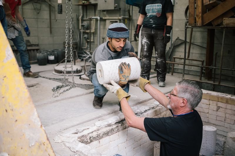 Faculty helps student lift their bronze cast sculpture