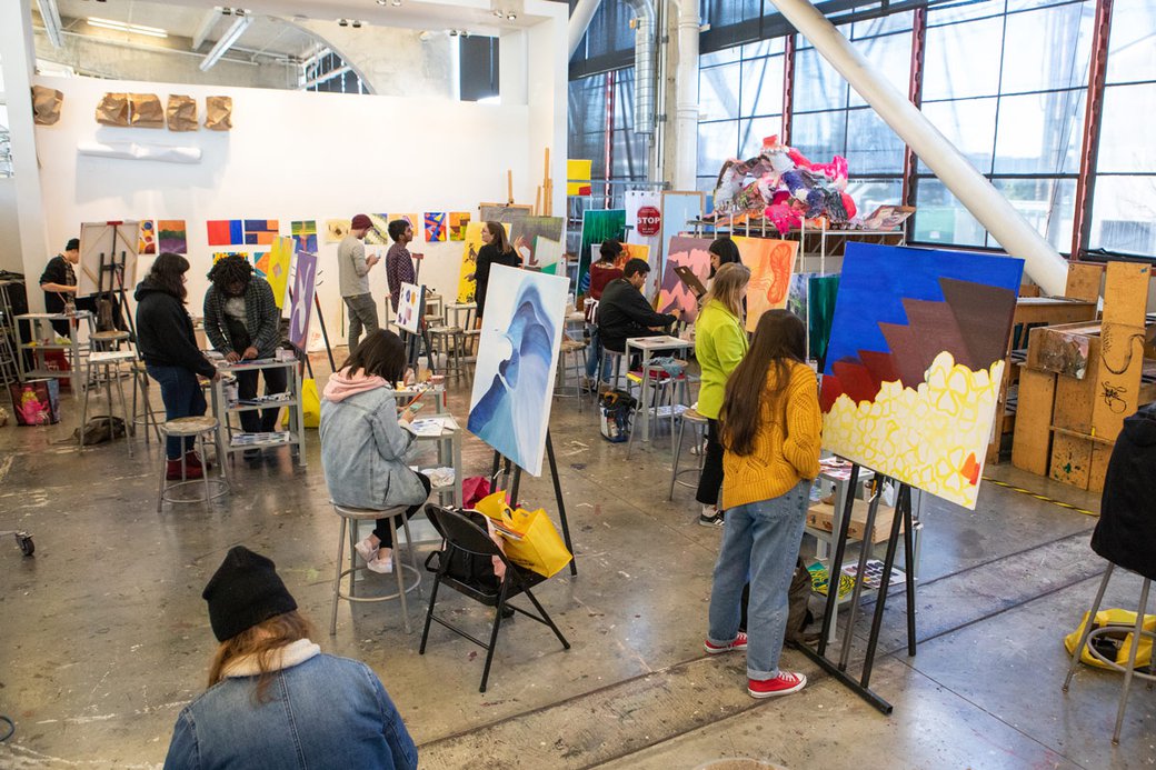 A studio full of students working on canvas paintings