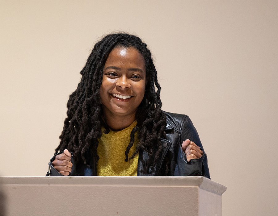 jasmyn McClelland reads at a podium in the Humanities and Sciences Graduate Center.