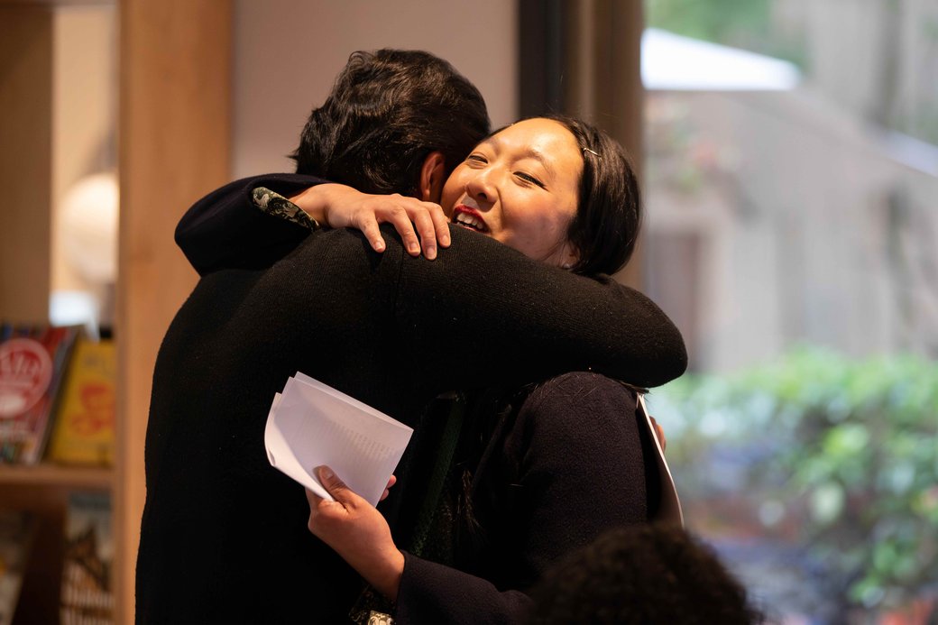 Two people embrace after a reading.