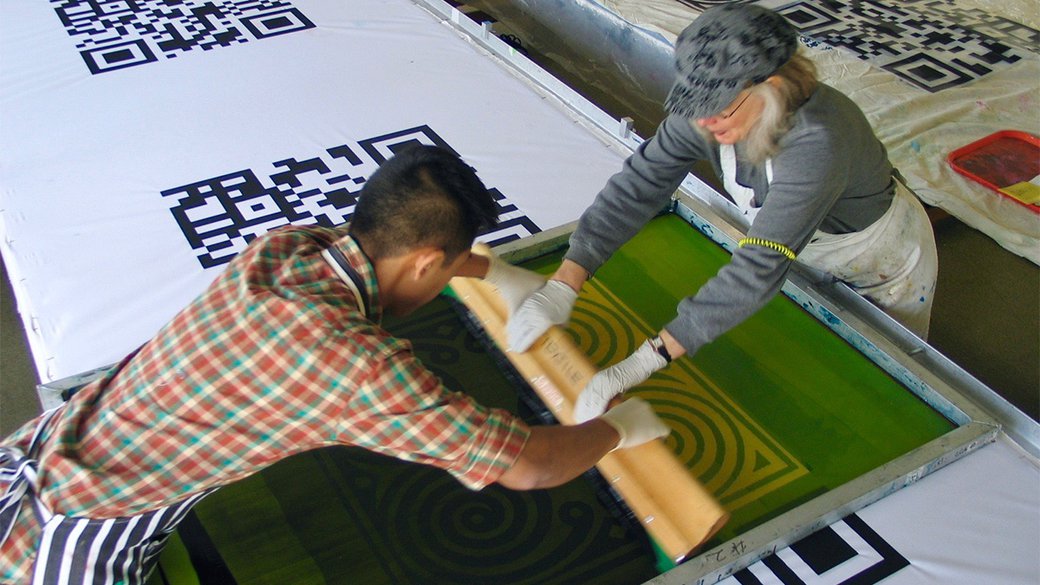 Two students screen printing a large banner.